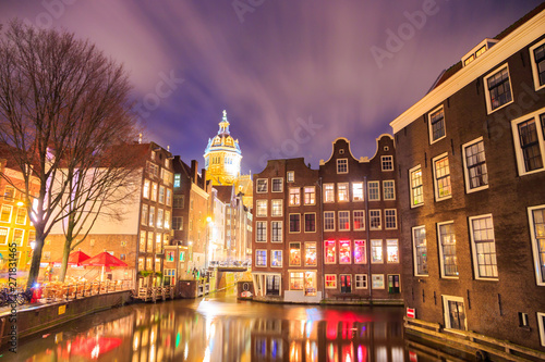Blurred dramatic night sky over traditional historical buildings on a canal, by the Armbrug bridge, in Amsterdam, Netherlands, with the Basiliek van de Heilige Nicolaas (Church of Saint Nicholas). photo