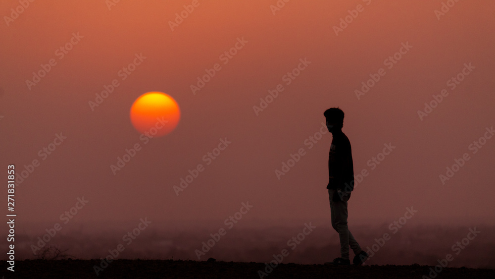 Man standing besides the sun during sunset