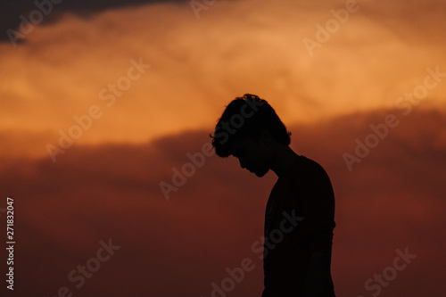 Silhouette of man standing in front of dramatic orange sky during sunset