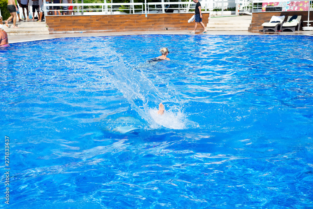 Man jumping in the swimming pool. Summer vacation A lot of splashes.