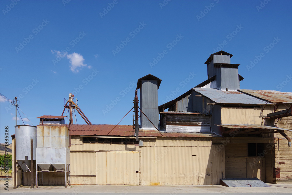 Partial view of an old California feed and grain warehouse with bright blue sky and a clouds above Partial view of an old California feed and grain warehouse with bright blue sky and a clouds above