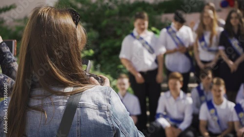 Woman shoots graduates on the phone at school close up