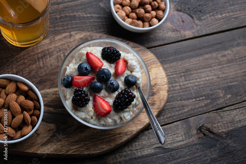 Fototapeta Naklejka Na Ścianę i Meble -  healthy breakfast. oatmeal with strawberries, blueberries, blackberries, almonds and hazelnuts with dried fruit compote