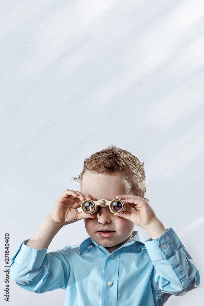 boy in a light shirt looking through binoculars on a light background