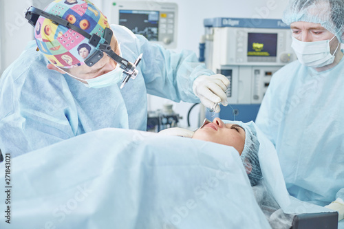 Several doctors surrounding patient on operation table during t