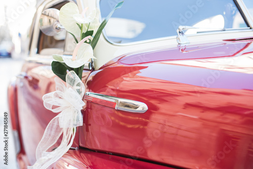 Wedding bouquet on red vintage wedding car.