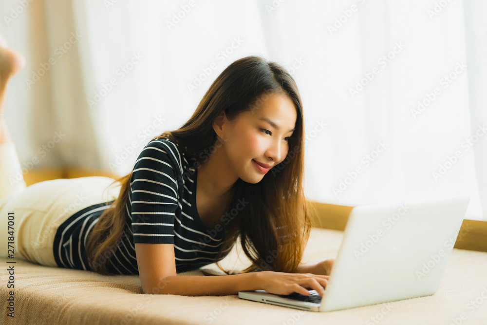 Portrait beautiful young asian woman using computer notebook or laptop on sofa in living room Portrait beautiful young asian woman using computer notebook or laptop on sofa in living room