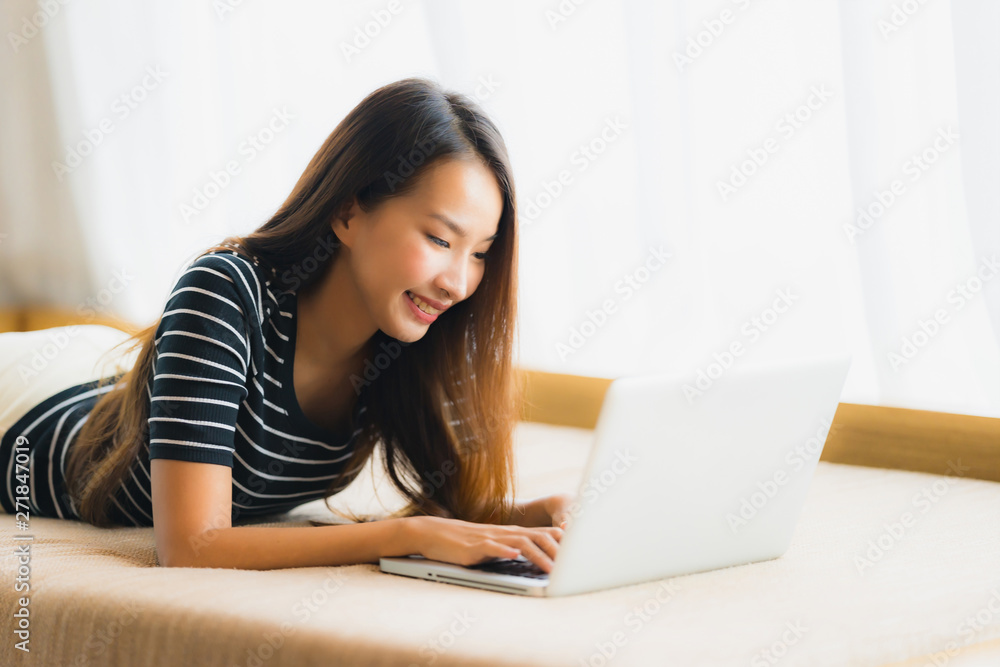 Portrait beautiful young asian woman using computer notebook or laptop on sofa in living room Portrait beautiful young asian woman using computer notebook or laptop on sofa in living room