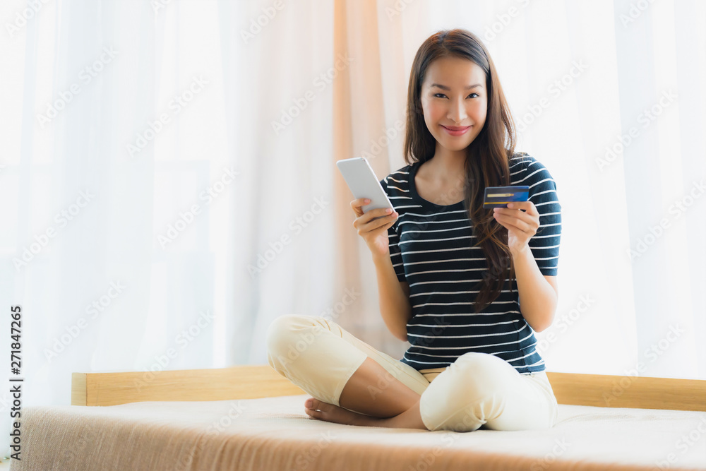 Portrait beautiful young asian woman using mobile or smart phone with credit card for shopping on sofa Portrait beautiful young asian woman using mobile or smart phone with credit card for shopping on sofa