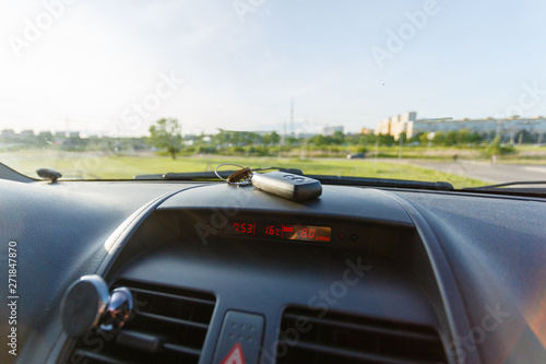 Closeup inside vehicle of wireless key ignition. Start engine key. Car key remote in black dashboard interior. Sunlight background. Modern car Interior details. Car detailing. Keys close up