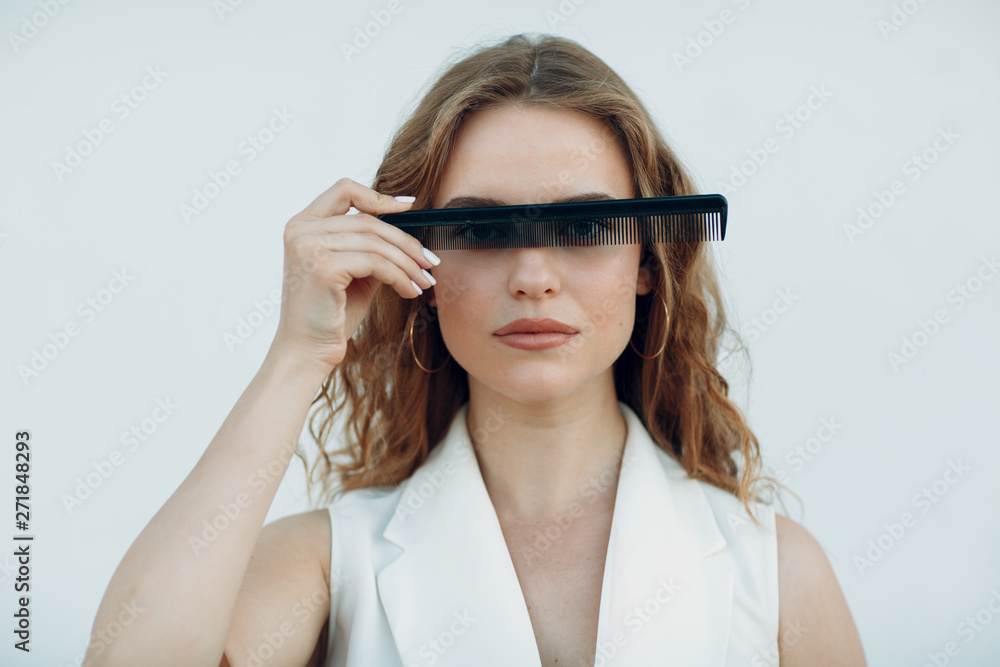 Portrait of young positive woman with curly hair with transparent comb at her face Portrait of young positive woman with curly hair with transparent comb at her face