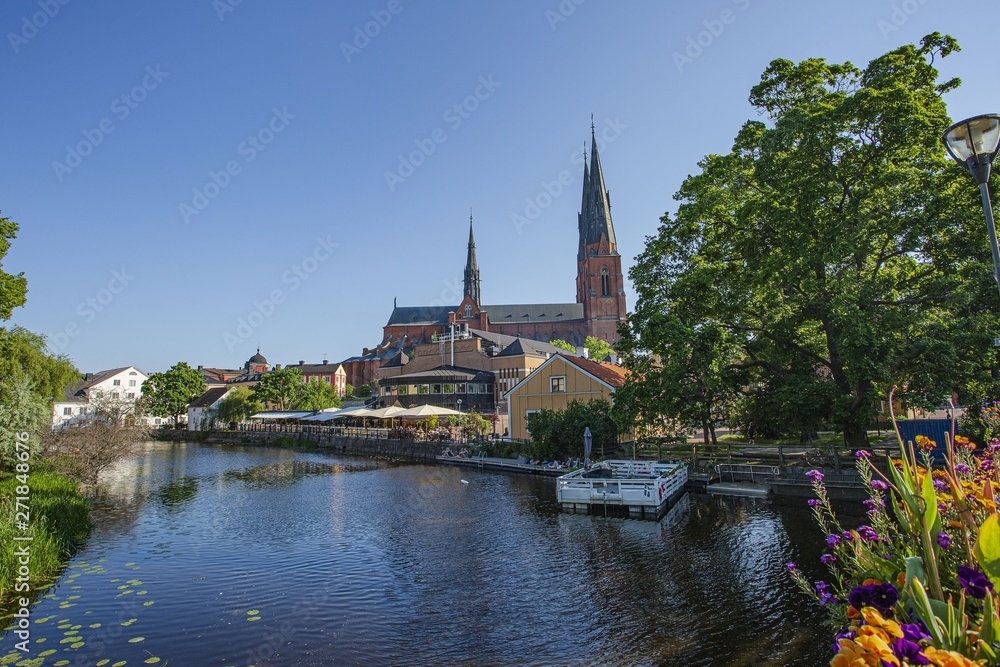 Beautiful view city landscape with small river and old church on cloudless blue sky background.