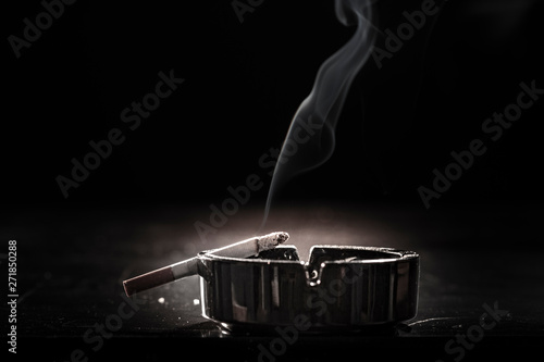 Closeup of cigarette on ashtray with a beautiful wisp of smoke photo