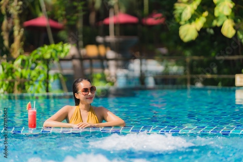 Portrait beautiful young asian woman leisure relax smile with watermelon juice around swimming pool in hotel resort