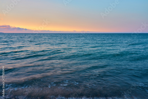 Waves on a pebble beach on a sunset. Natural background.
