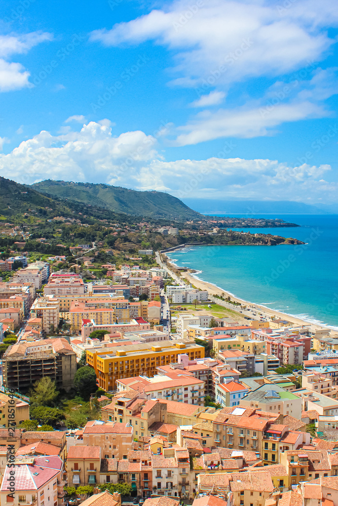 Fototapeta premium Stunning view of coastal city Cefalu in Sicily, Italy captured on a vertical picture. The city on Tyrrhenian coast surrounded by rocky hills is a popular summer vacation destination