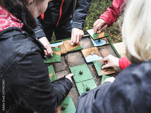 Adults putting together pieces of outdoor wooden puzzle. Forest of Senses (Wald der Sinne), educational  walk in Altenberg. Styria, Austria, May 20, 2019.