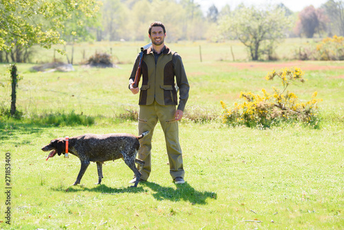 portrait of man holding gun with his dog photo