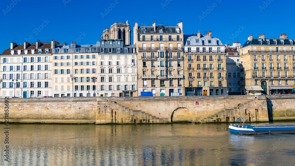 Paris, beautiful houses on the quay aux Fleurs, with a view of the Seine, typical facades of the French capital, and the Notre-Dame towers in background
