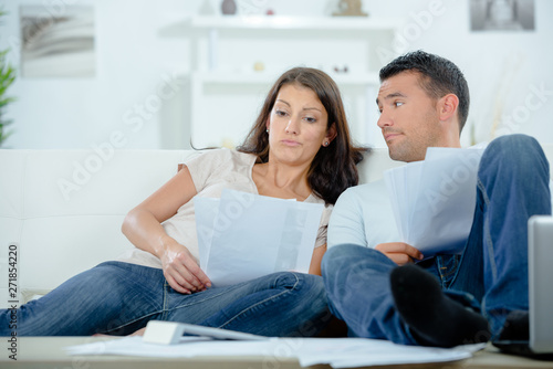 busy couple with papers and calculator at home