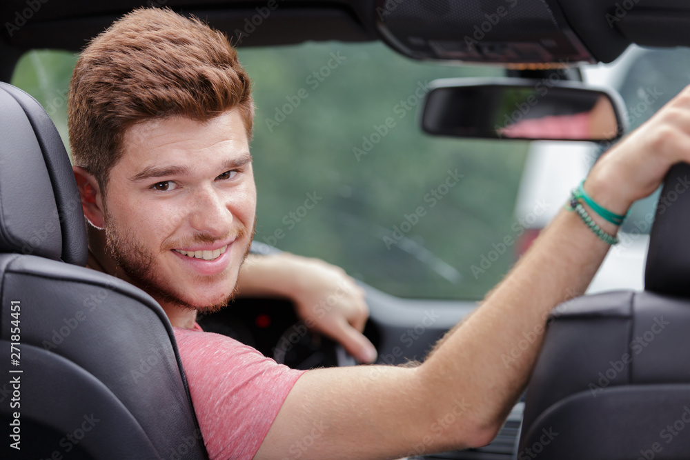 young man looking back while parking his new car