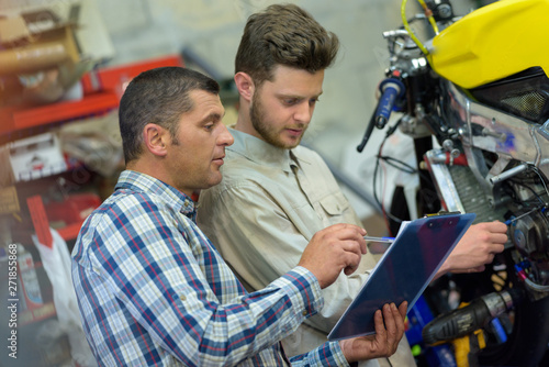 motorcycle mechanic repairing engine under supervisors guidance