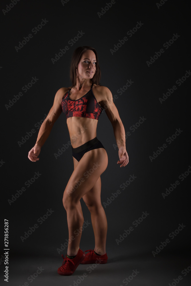 Sporty woman does the exercises on black background