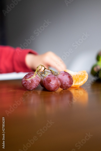 Baby s hand manipulating different fruits on a wooden table photo