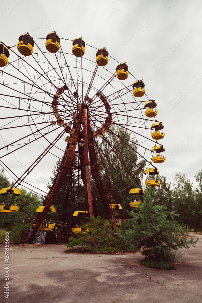 Chernobyl Exclusion Zone, Ukraine. Destroyed abandoned ghost city Pripyat ruins after disaster. Old broken rusty metal yellow carousel wheel, amusement park. Fallout lost town.
