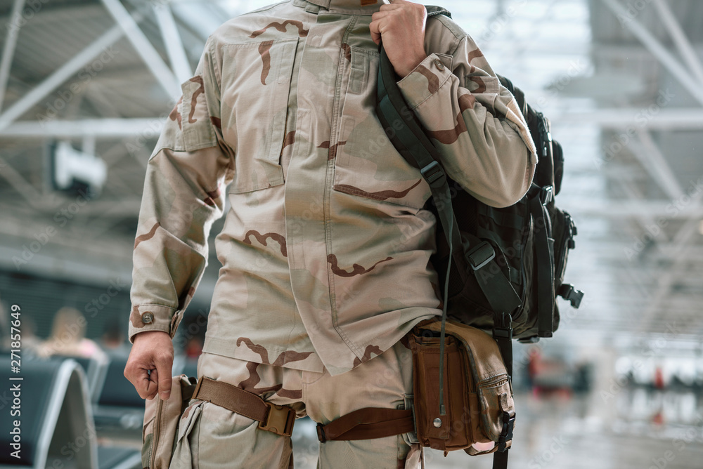Low angle of American soldier in camouflage keeping backpack Low angle of American soldier in camouflage keeping backpack