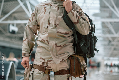 Low angle of American soldier in camouflage keeping backpack