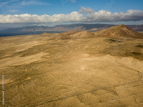 Aerial view of a desert landscape on the island of Lanzarote, Canary Islands, Spain. Mountains of the village of Soo and in the background Famara. Reliefs and volcanoes on the horizon