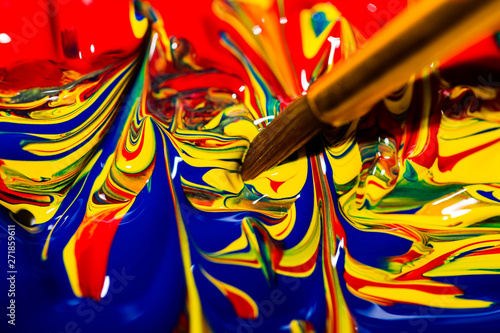 Artist's brush tip dipping into a mix of primary colors forming a vibrant swirling pattern of chaos.