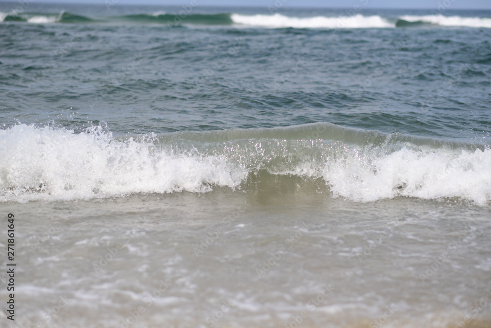 closeup on waves hitting the beach on a sunny summer day