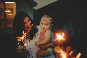 Mom doing sparkler firework with baby girl
