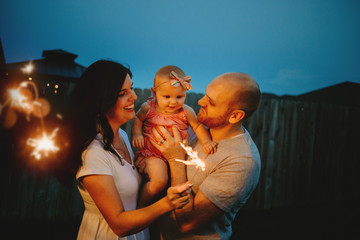 Happy Couple doing sparkler fireworks with baby