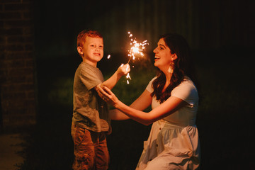 Mother doing sparkler firework with son