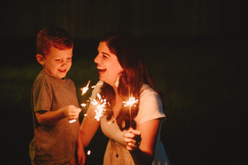 Mother doing sparkler firework with son
