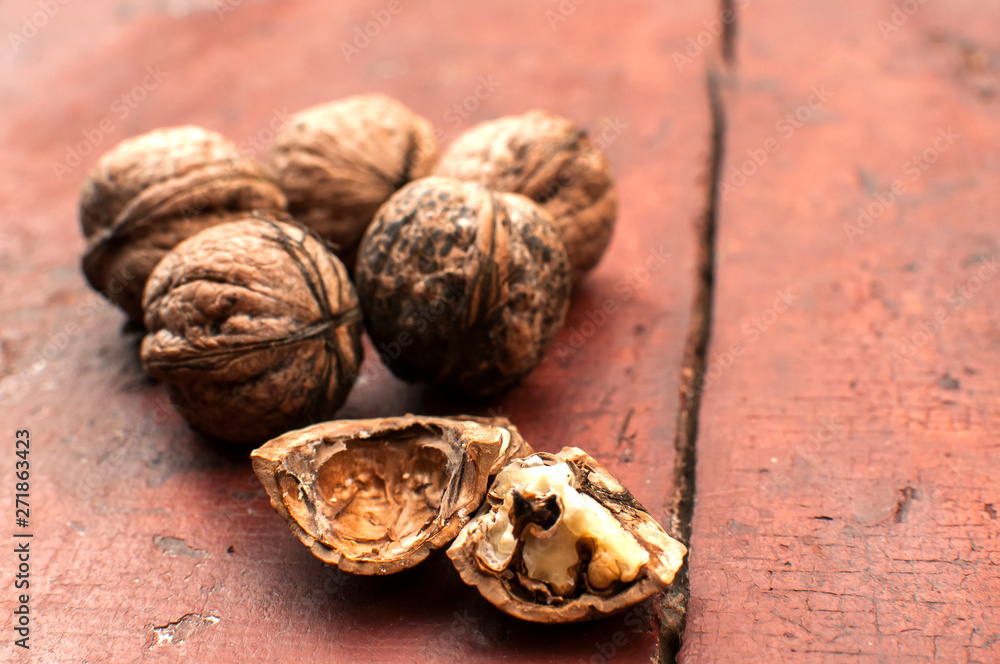 Whole and cracked walnut shells and cores closeup on old wooden boards surface as background Whole and cracked walnut shells and cores closeup on old wooden boards surface as background