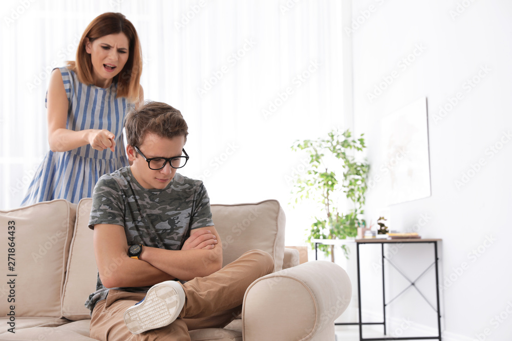 Mother scolding her teenager son at home Mother scolding her teenager son at home