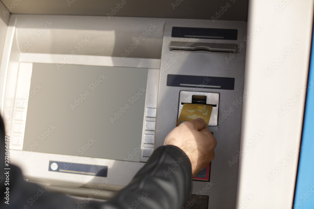 Man inserting credit card into cash machine outdoors, closeup Man inserting credit card into cash machine outdoors, closeup