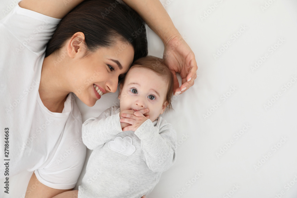 Portrait of mother with her cute baby lying on bed, top view. Space for text Portrait of mother with her cute baby lying on bed, top view. Space for text