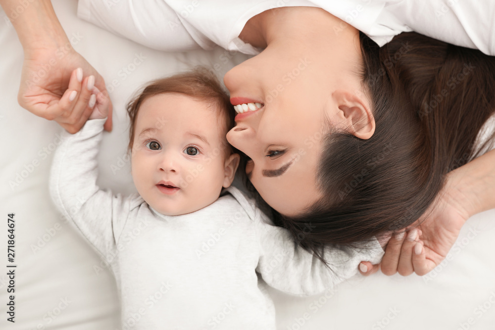 Portrait of mother with her cute baby lying on bed, top view Portrait of mother with her cute baby lying on bed, top view