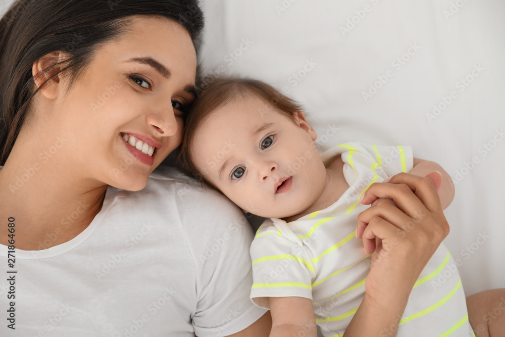Portrait of mother with her cute baby lying on bed, top view Portrait of mother with her cute baby lying on bed, top view