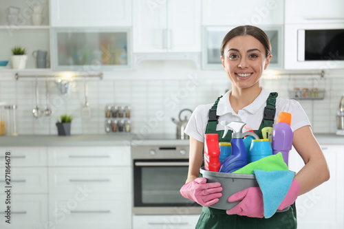 Photos Portrait of young woman with basin of detergents in kitchen