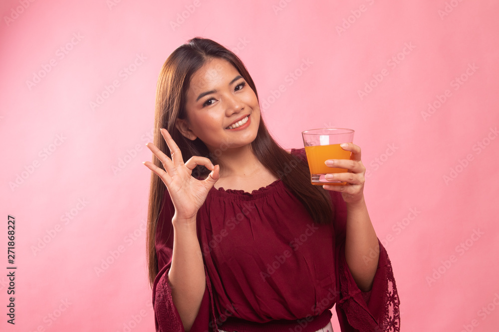 Young Asian woman drink orange juice show OK sign. Young Asian woman drink orange juice show OK sign.