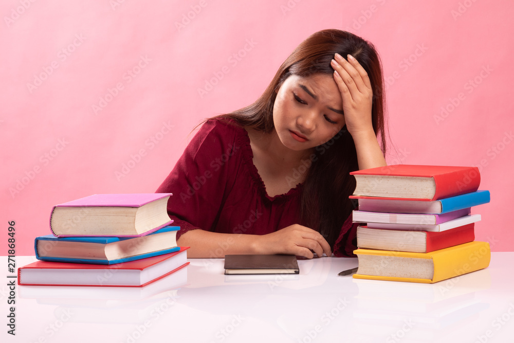 Exhausted Young Asian woman read a book with books on table. Exhausted Young Asian woman read a book with books on table.