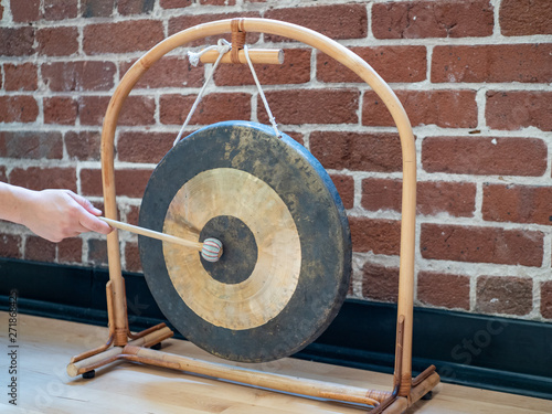Φωτογραφία Small suspended gong sitting hit with mallet by hand of a woman