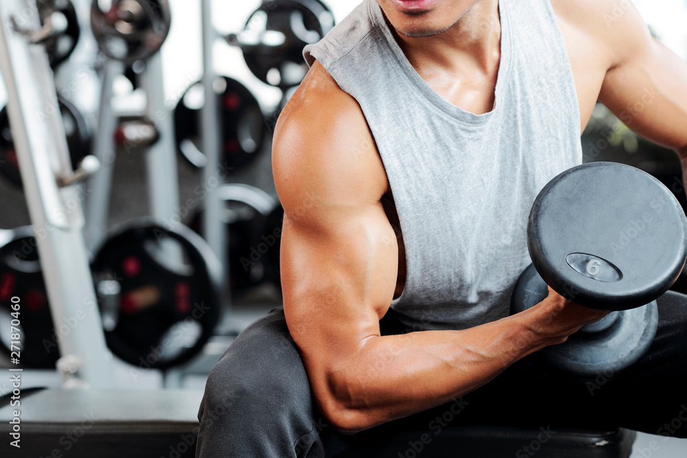 Fit strong man doing biceps curl in gym Fit strong man doing biceps curl in gym