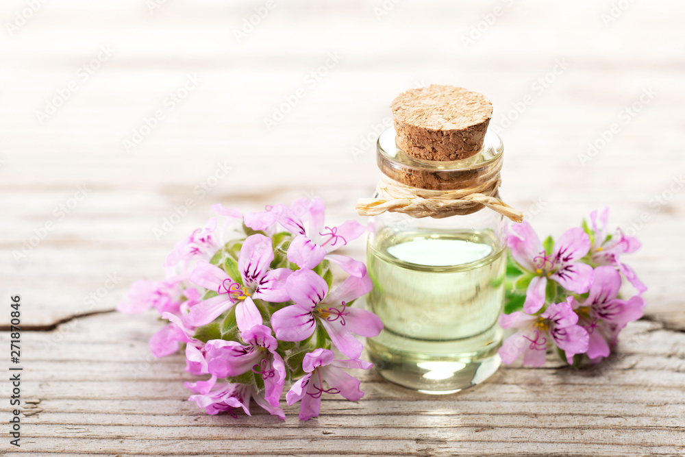 Geranium essential oil with fresh geranium flowers, on the old wooden board Geranium essential oil with fresh geranium flowers, on the old wooden board